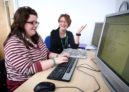 AmyCrossland.jpg, 2 women say at computers, smiling and talking
