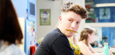 A boy with a pencil in his mouth