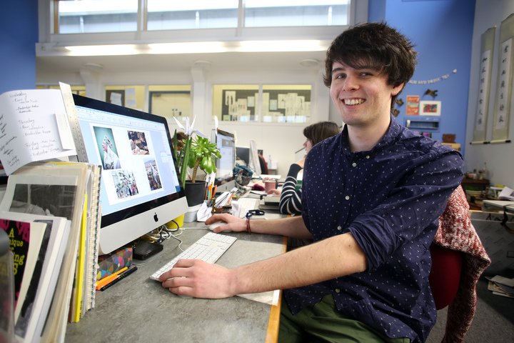 A student at a computer smiles at the camera. A student at a computer smiles at the camera.
