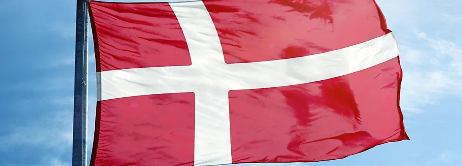 The flag of Denmark at the top of a flag pole.