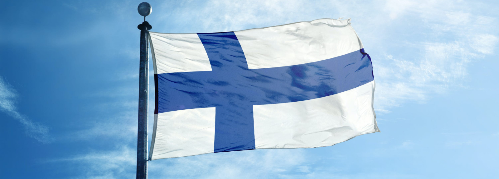 The rear end of a boat on the water with the Finnish flag hanging from the back.