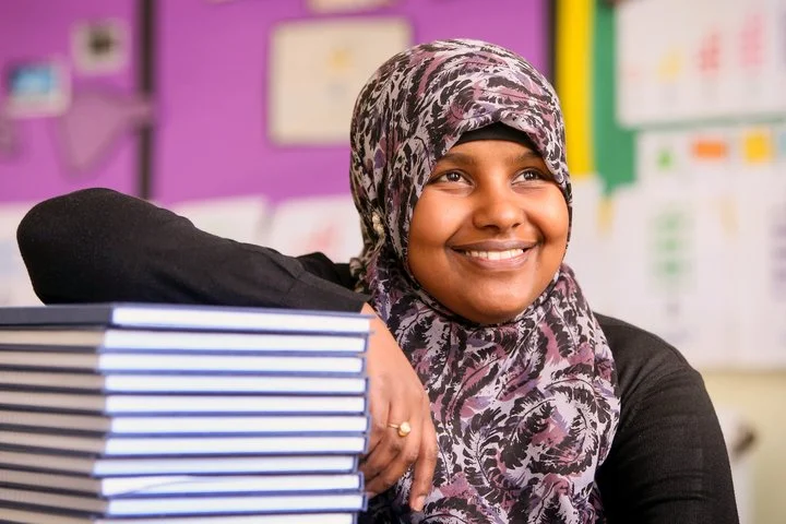 A student leans against a stack of books.