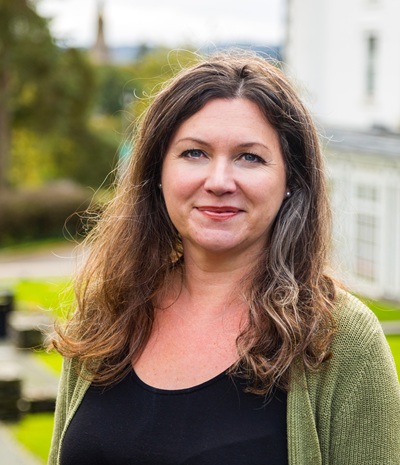 A woman with long brown hair and a green cardigan