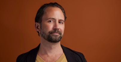 A head shot of a man with dark hair and beard