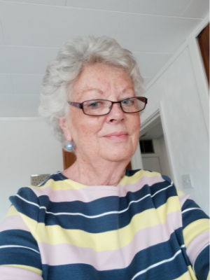 Head and shoulders shot of lady with grey hair and big glasses in a striped top