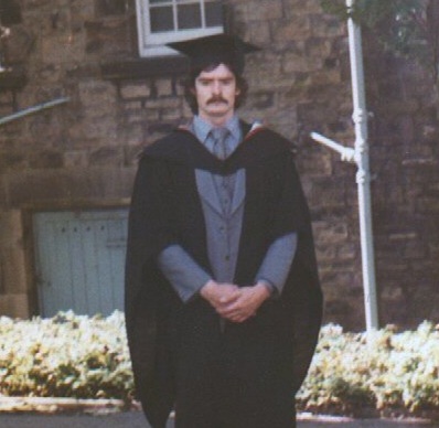 A 1970s image of a man with dark hair in graduation cap and gown