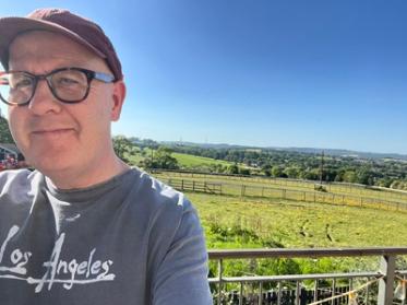 Man with glasses and baseball cap in a green landscape