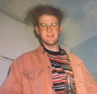 Man with glasses and orange shirt over a striped tshirt