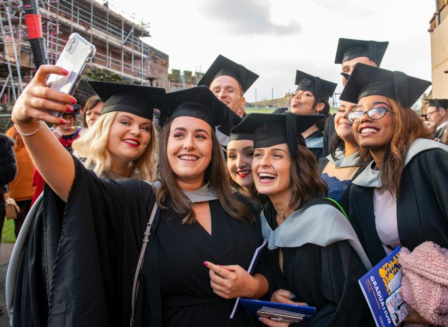A group of graduates take a selfie together.