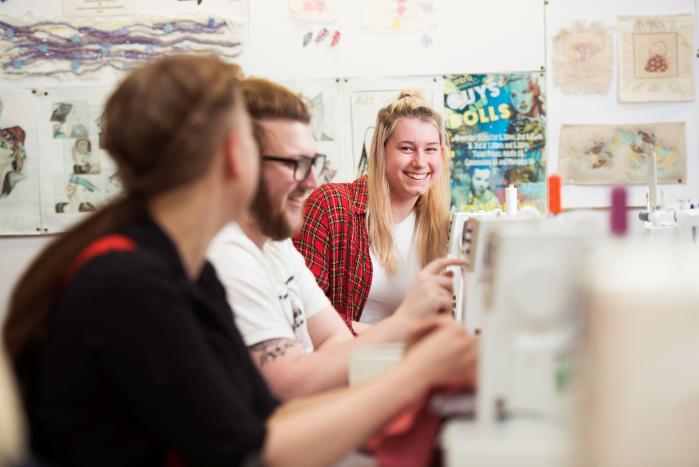 Students chatting by while sewing.
