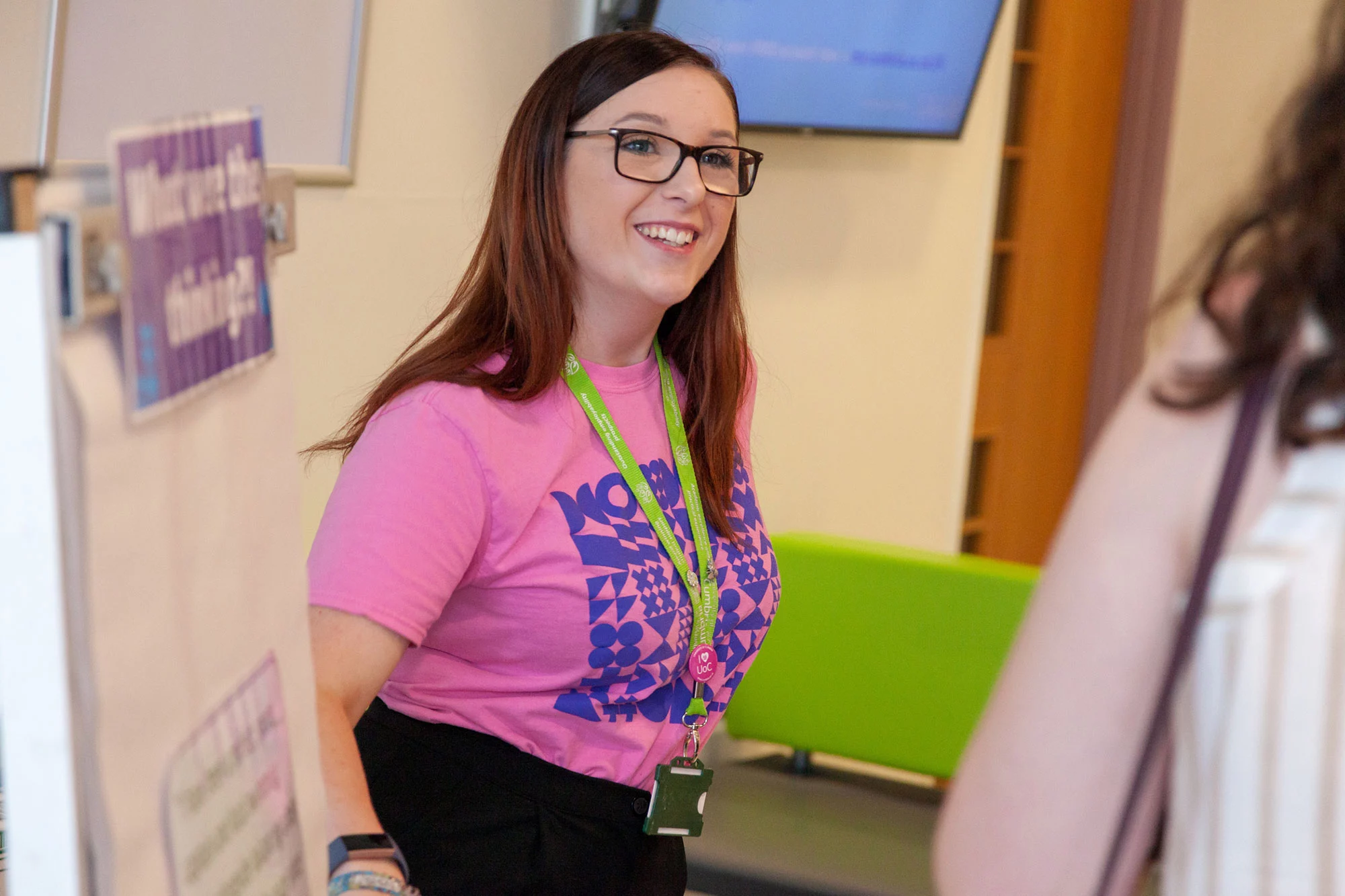 A UoC student helps people at an open day.