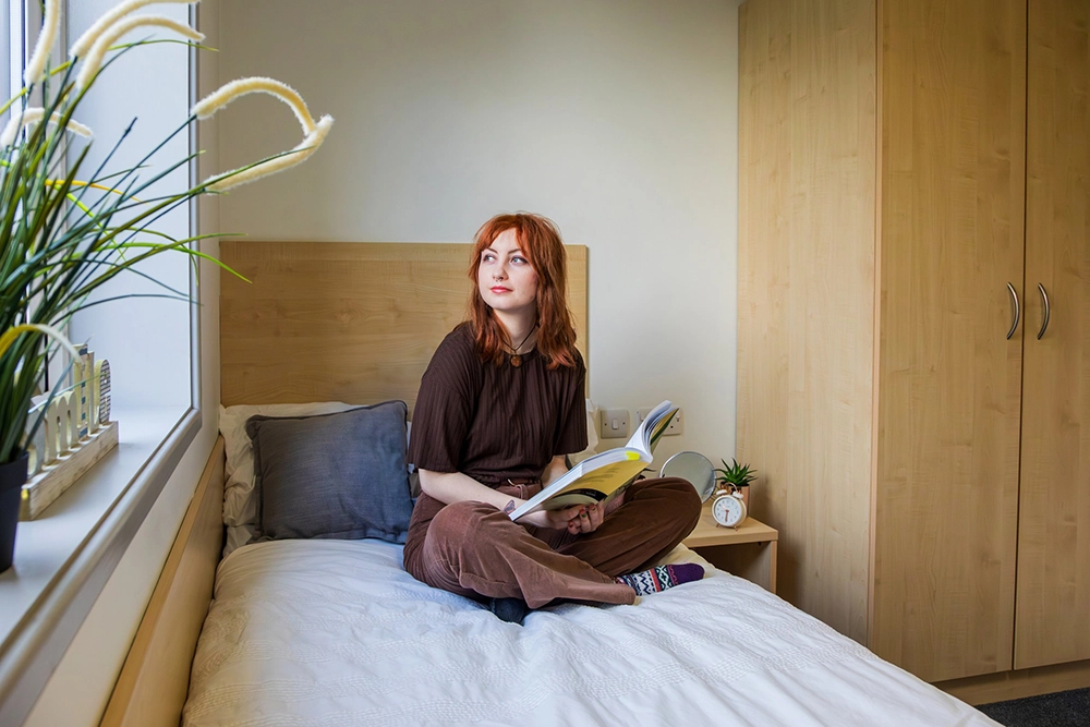 University student seating on a bed