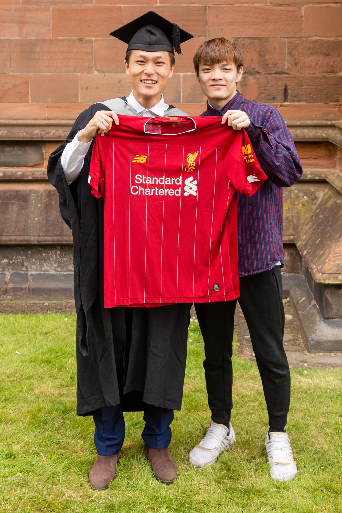 Li Zhen, Student holding football shirt next to family member at graduation