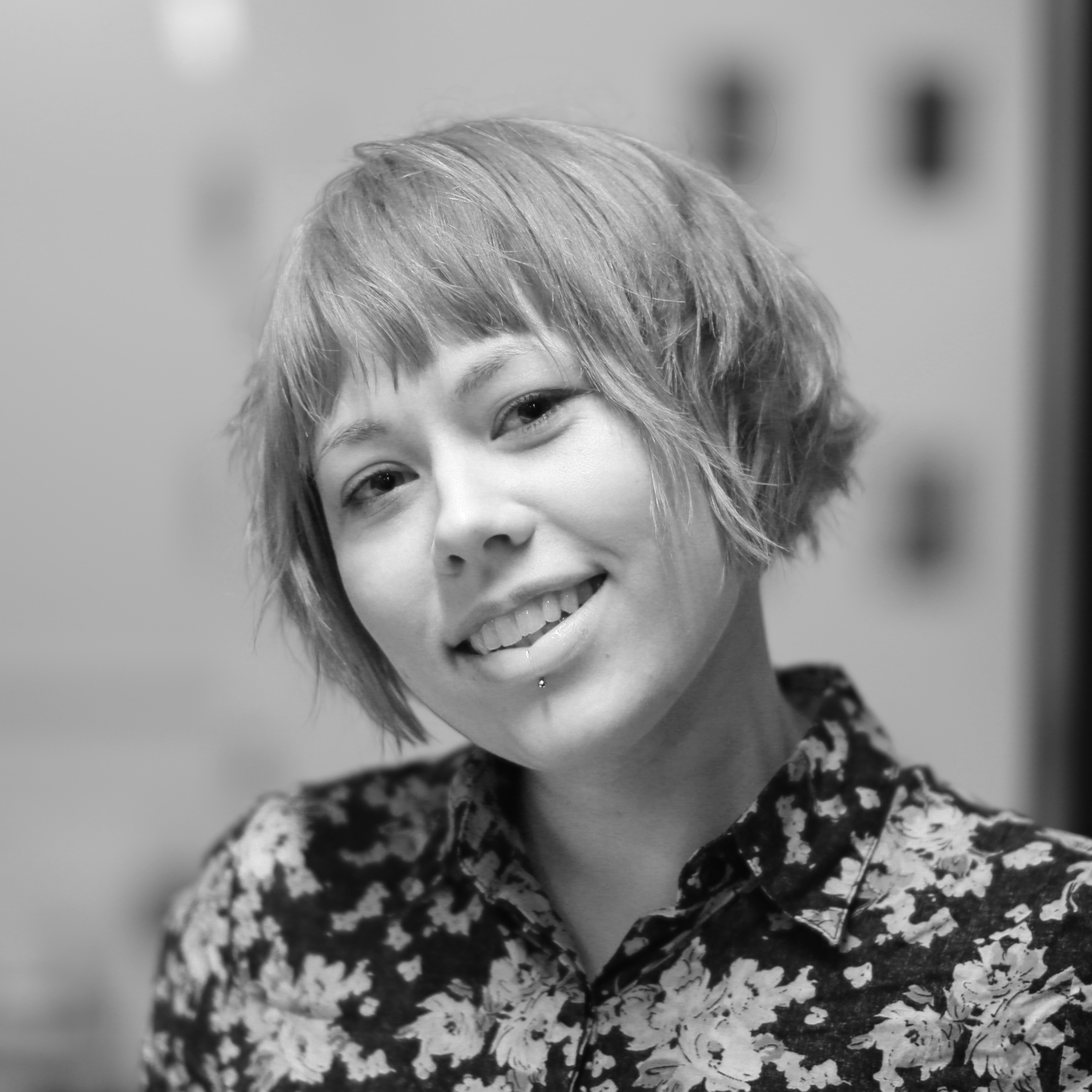 A black and white photo of a female with short hair smiling at the camera. 