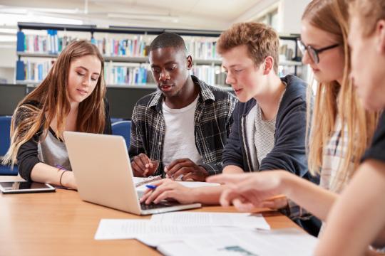 Stock Image Study Group, Four students studying at a table with laptop