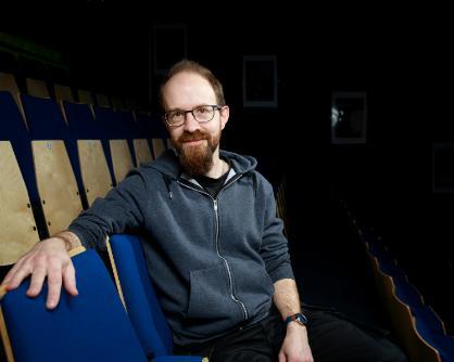 Tony Sharpe - Stanwix Theatre Technician, A portrait of a gentleman in a dark shirt sitting in a theatre.