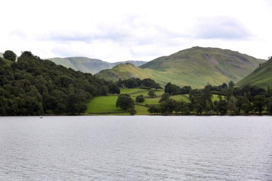 13_things_lakes, A landscape photo with a large lake in the foreground and hills and greenery in the background.