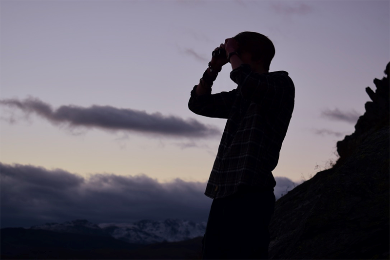 How to Choose a University 1, A person looking through binoculars towards the distance as the sun sets 