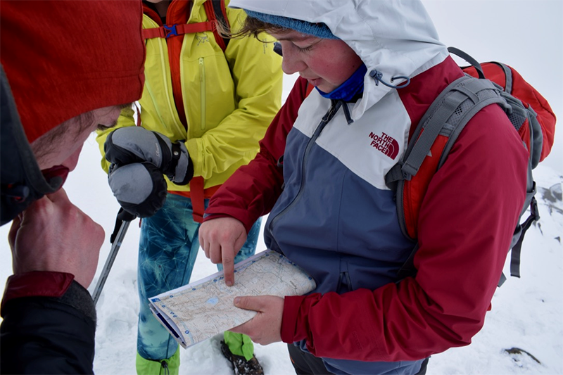 How to Choose a University 2, Three people looking at a map while hiking in snow 