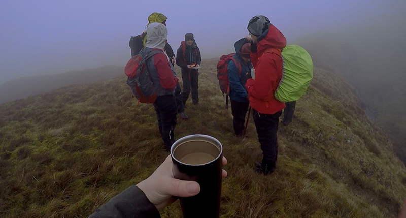 Ambleside Coffee Blog 4, Ambleside Coffee Blog: A group of people enjoying a hike in the damp weather. The person taking the photo is holding a warm cup of coffee.