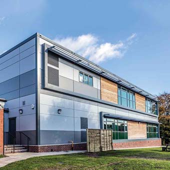  A photo of a campus building with white, grey and wooden slats across the front