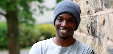 Male smiling in front of building 