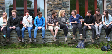 Group of people sat on a wall together smiling