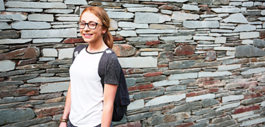 A girl smiling near a wall