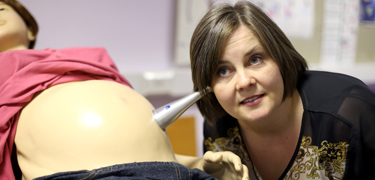 Woman listening to a model stomach in maternity ward