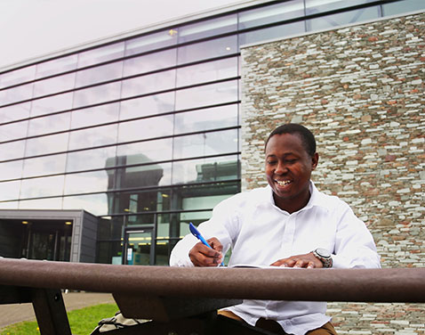 student sitting outside gateway Lancaster.  Original file name: international.jog