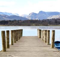 Pier, A wooden pier leading to a lake with hills in the background.