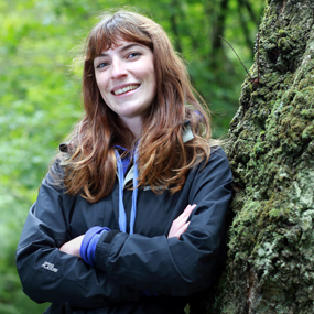 female smiling next to a tree
