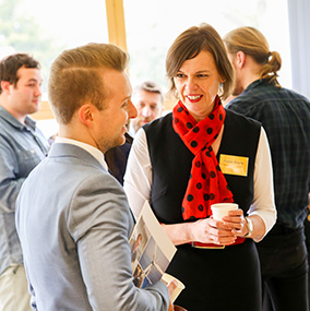 A woman and man discussing something in a room of people