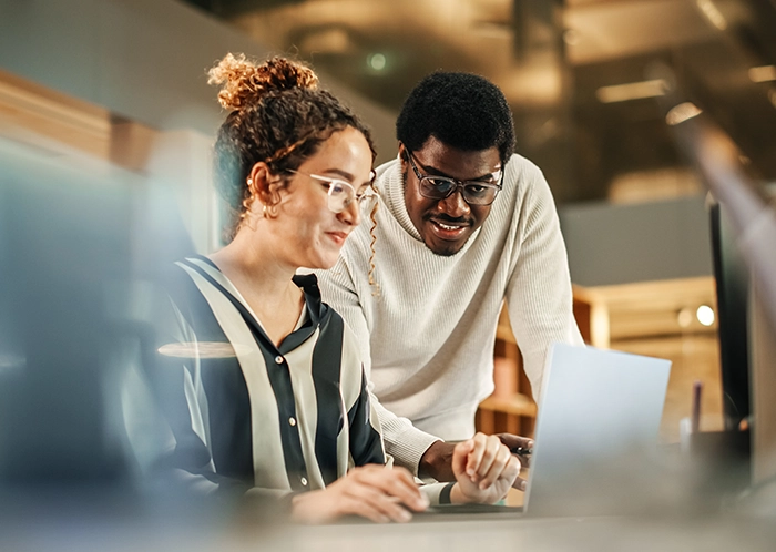 Two Creative Colleagues Using Laptop to Discuss Work Project at Office