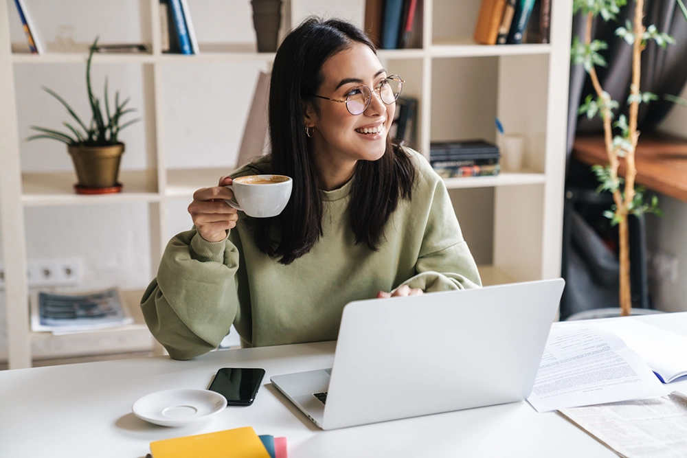 smiling university student with a laptop and a cup of tea