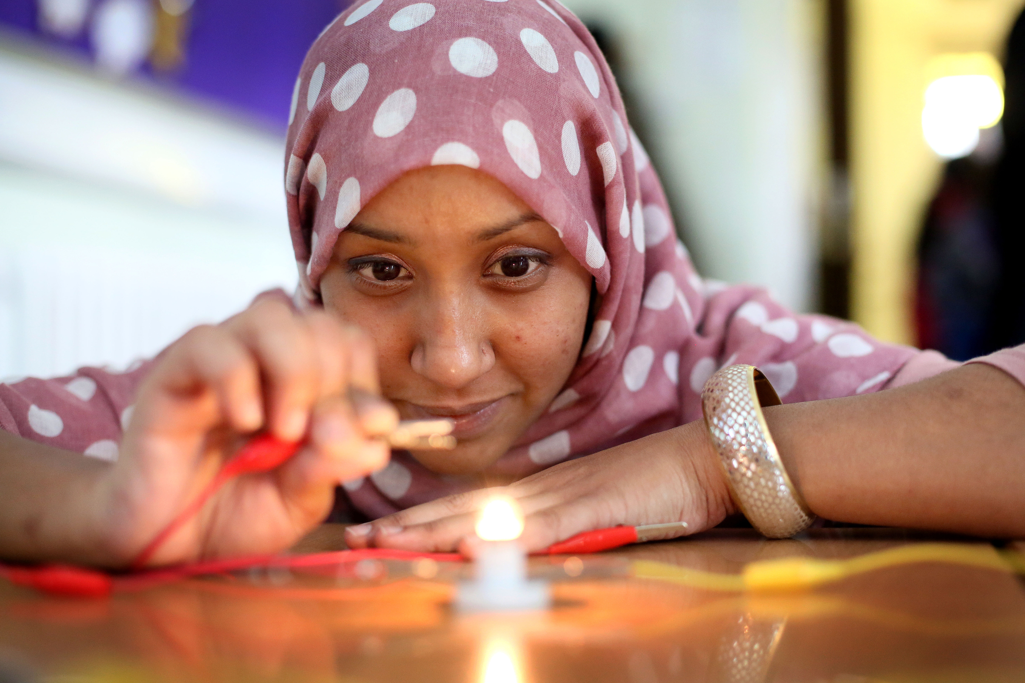 A women plays with a circuit to light a bulb.