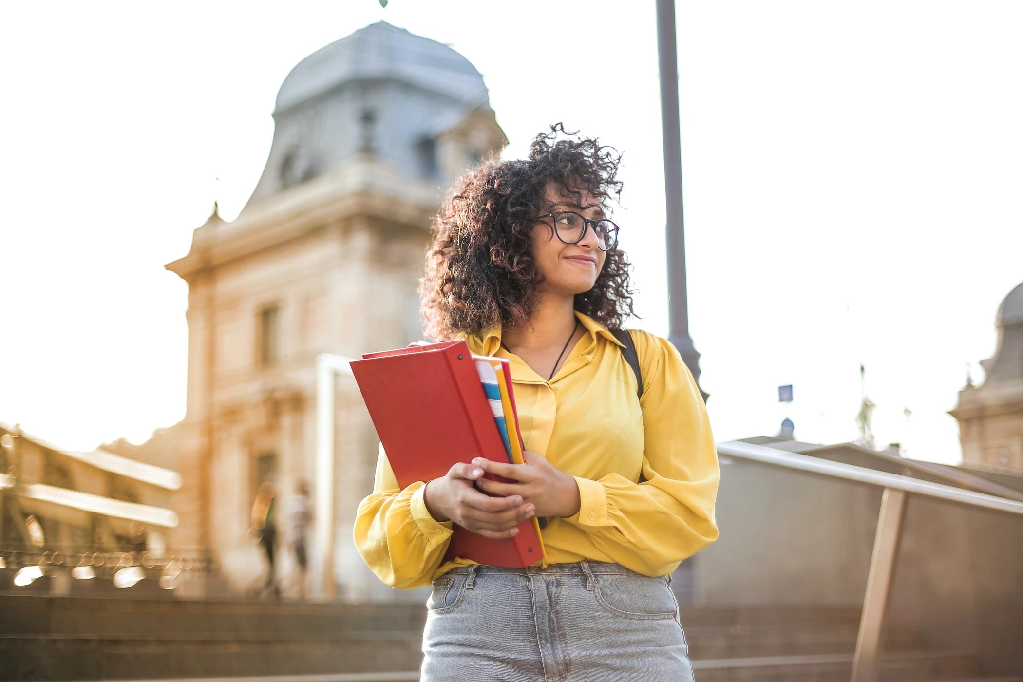 A student holds a text book in front of a monument. 