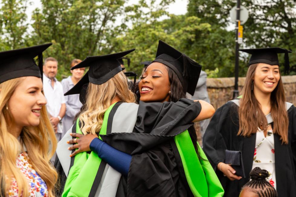 Two graduates hug outside.