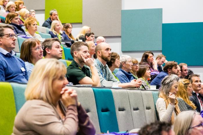 Health professionals sit in a lecture theatre.