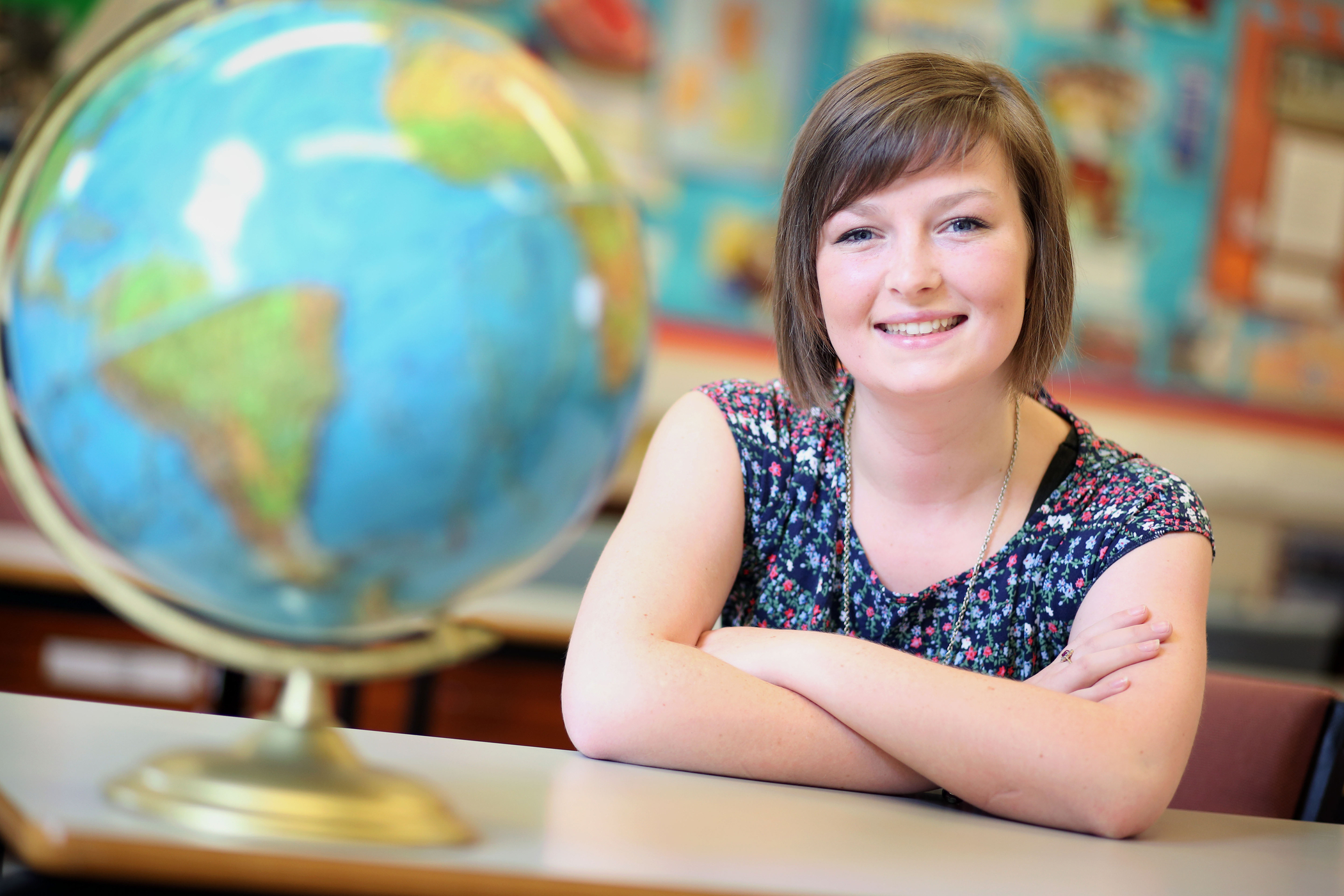A PGCE student sits smiling in a classroom