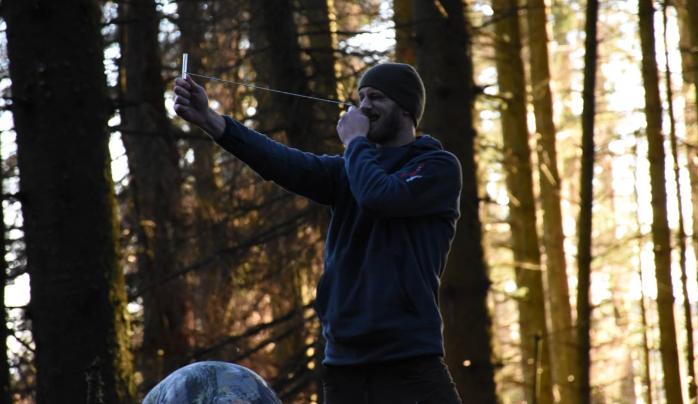 A man conducts research in the woods.
