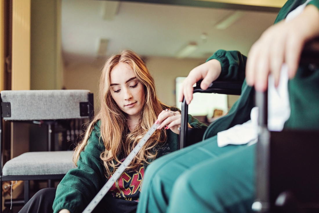 Health student helping with a person in a wheel chair.