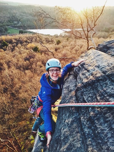 Student climbing rockface in a field Student climbing rockface in a field