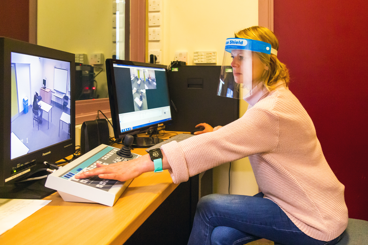 A technician using equipment to monitor a experiment in the next room