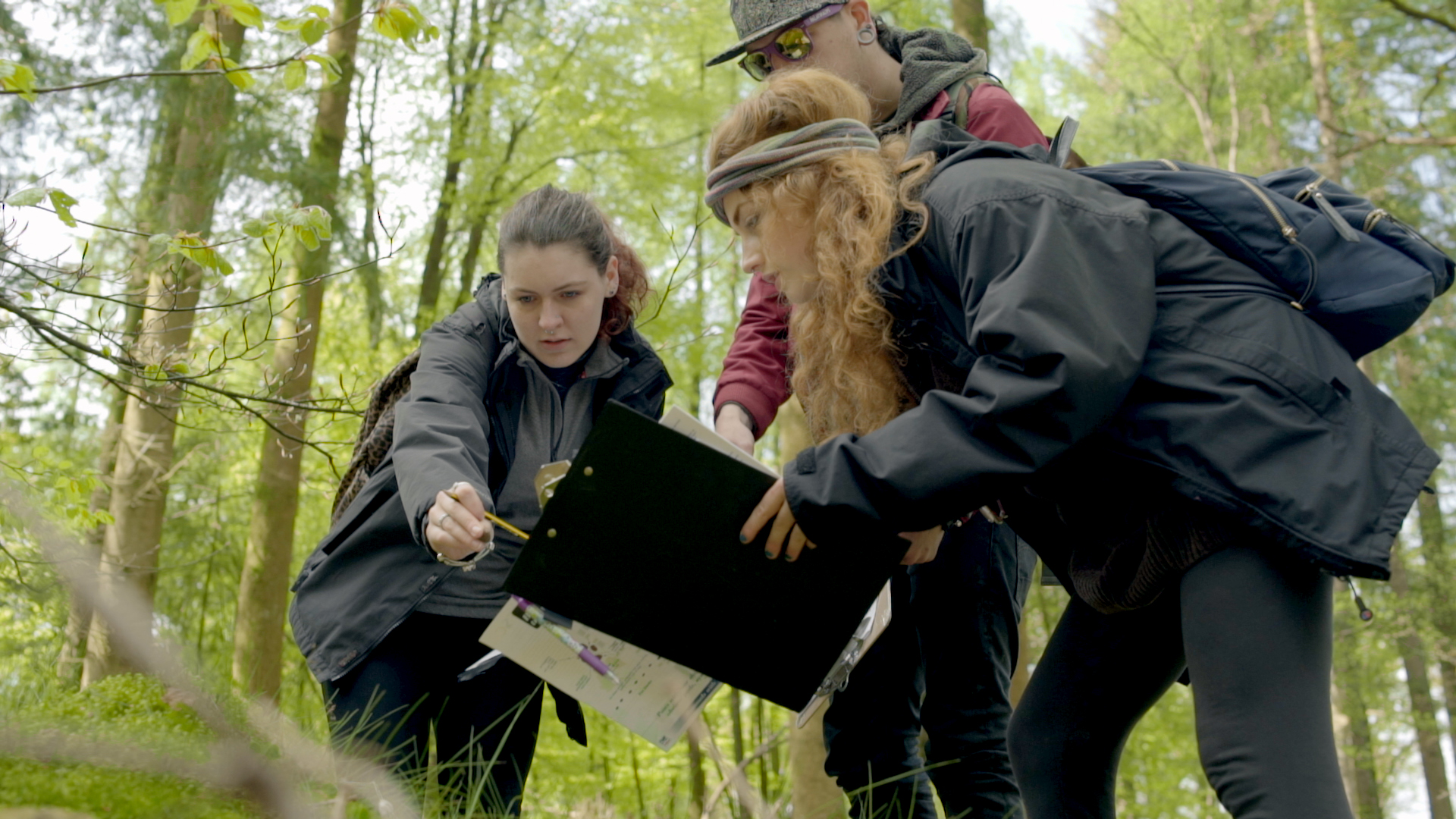 Students walk with a lecturer in the forest.