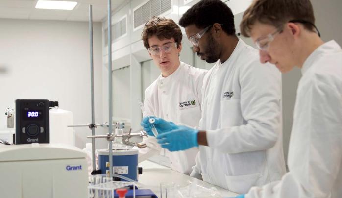 Three students using a test tube in a science lab