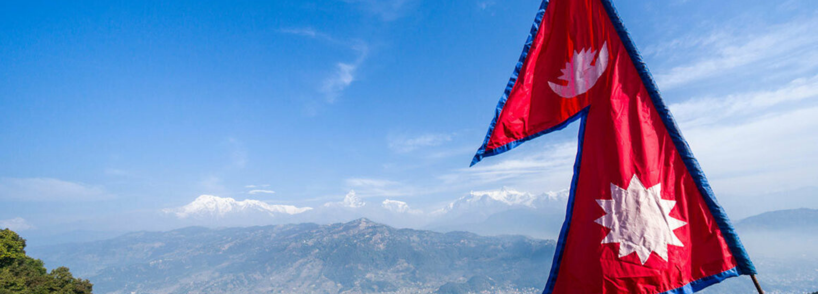 Flag of Nepal in front of a mountain.
