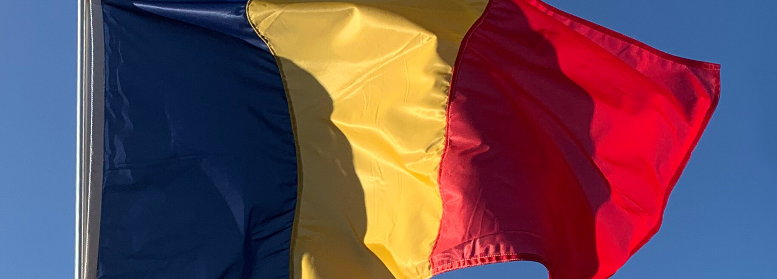 The Romanian flag on a flagpole.