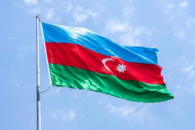 A picture of a flag pole with the Azerbaijan flag at the top, blowing in the wind.