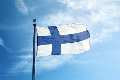 The rear end of a boat on the water with the Finnish flag hanging from the back.